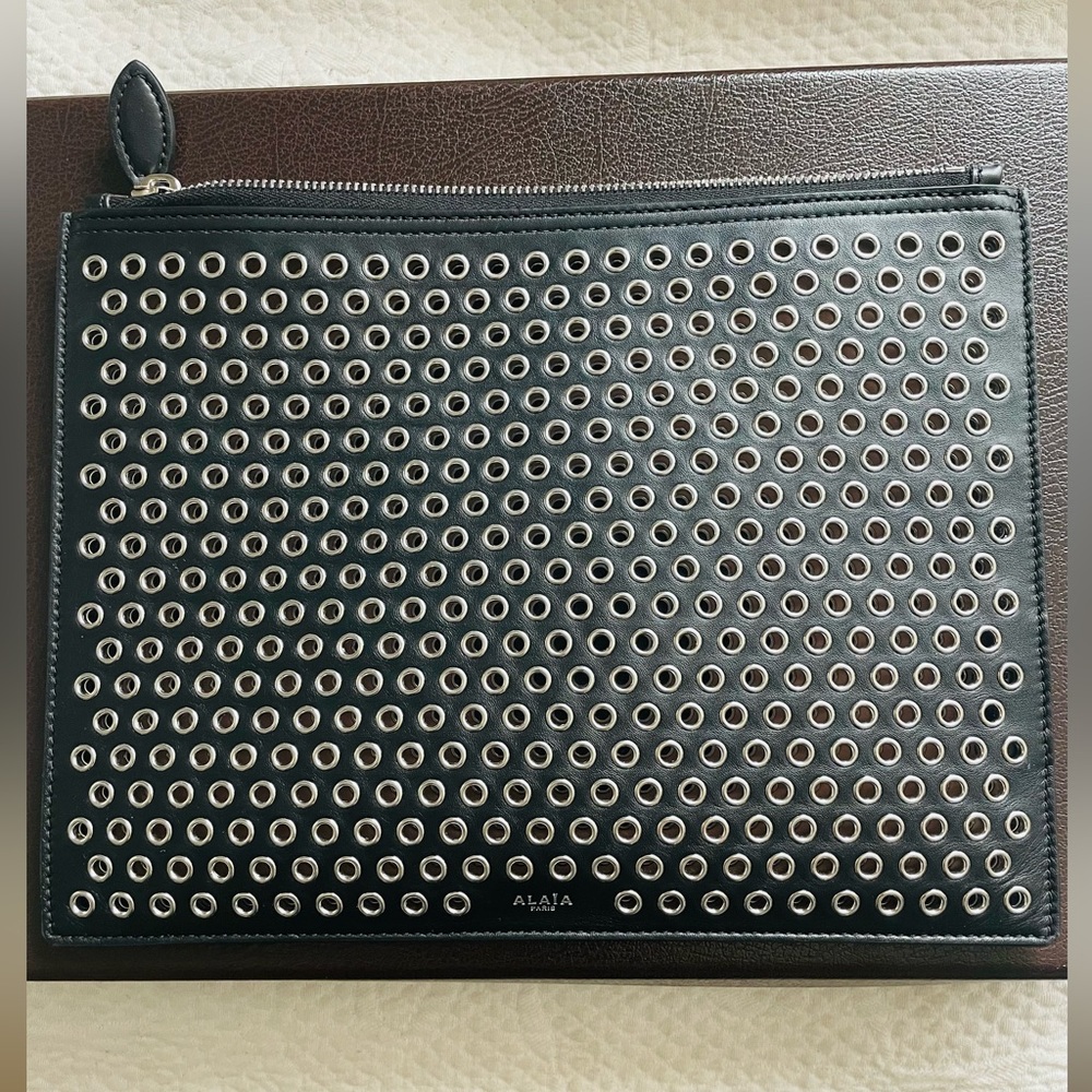 ALAÎA Black leather clutch with silver grommets.